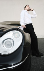 Businessman talks on his mobile phone beside his business car