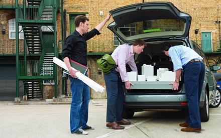 Architects load an architectural model into a car