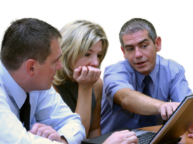 Three executives working on laptop. The main focus is on the woman, the man on the left is little soft focused.