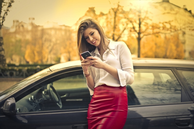 Businesswoman on her smart phone with car
